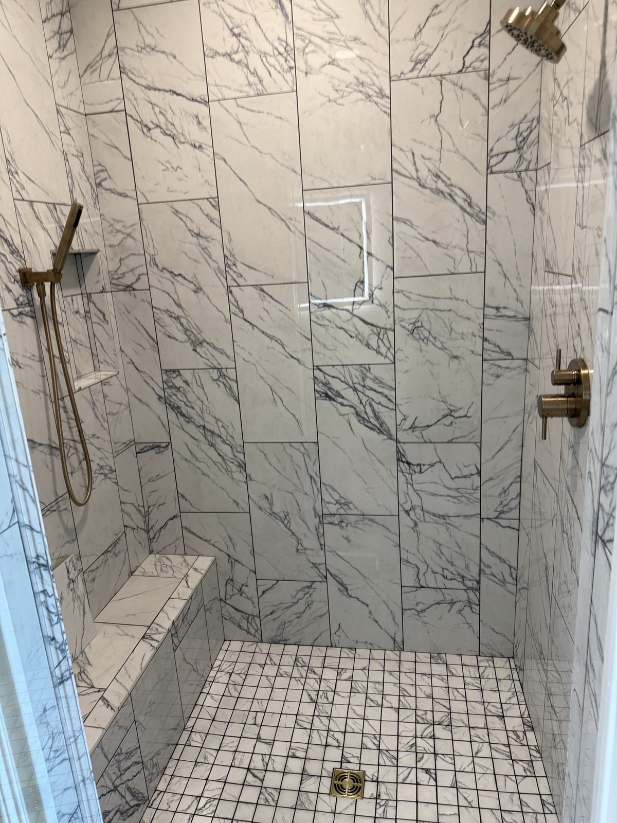 Custom tiled shower with multiple shower heads and a handheld sprayer