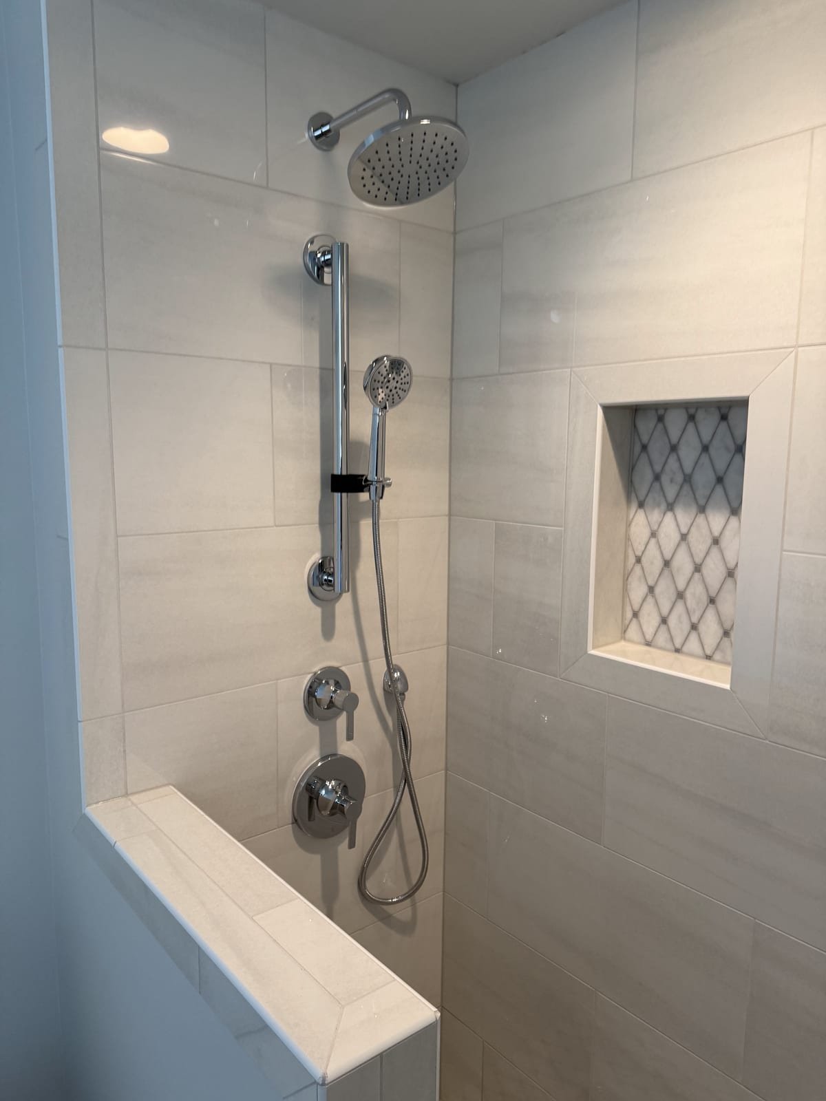 Shower installation with a fixed head and a handheld sprayer on a slide bar