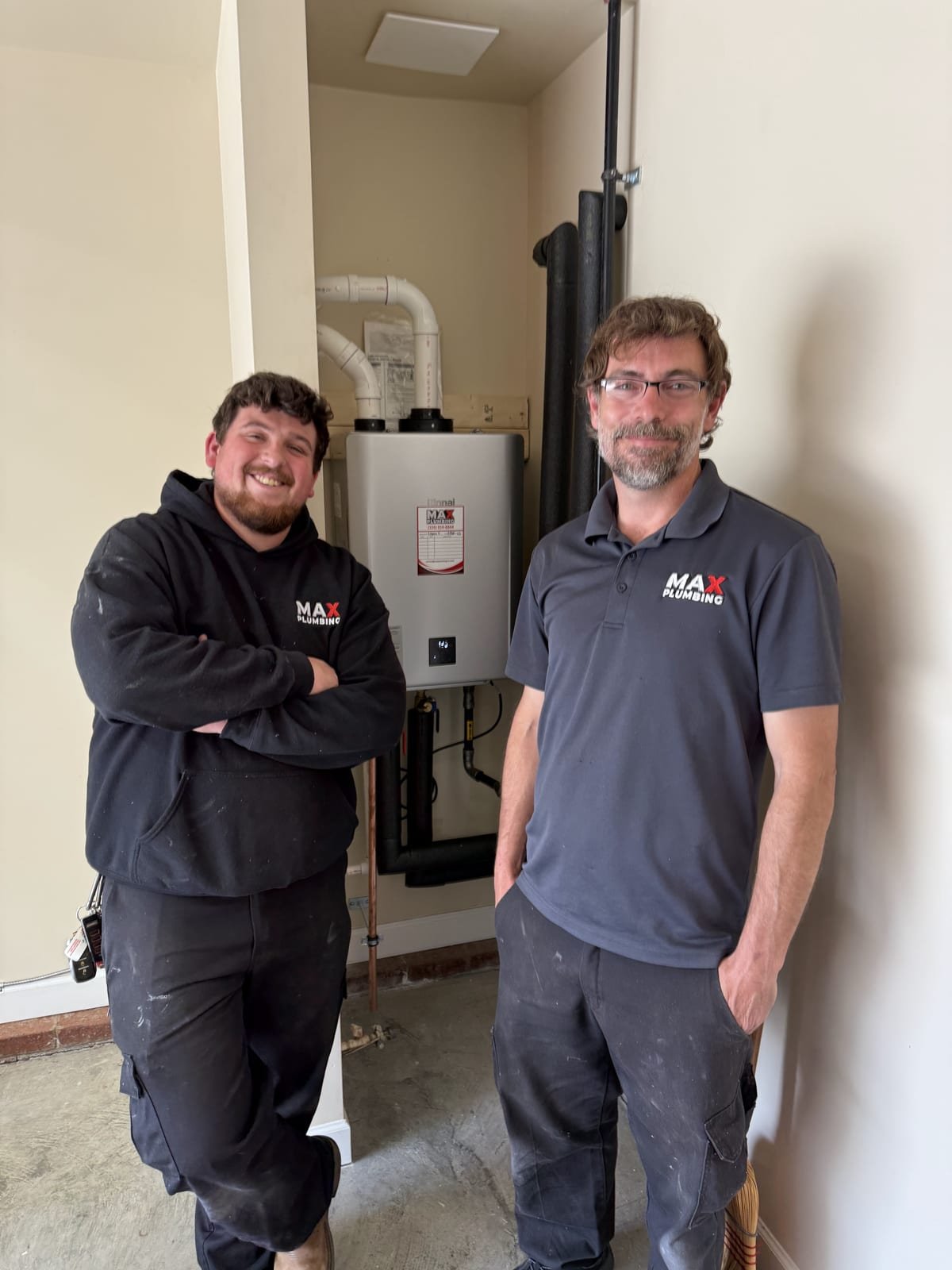 Two MAX Plumbing technicians at a completed tankless water heater installation