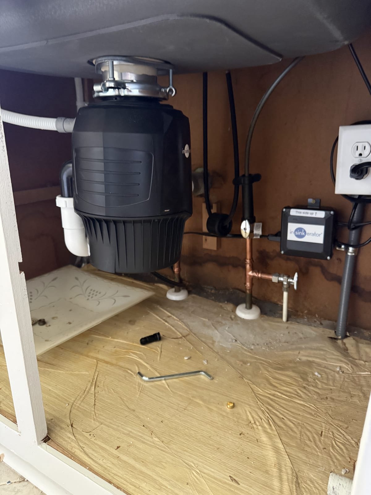 Garbage disposal installed under a kitchen sink with drain connections