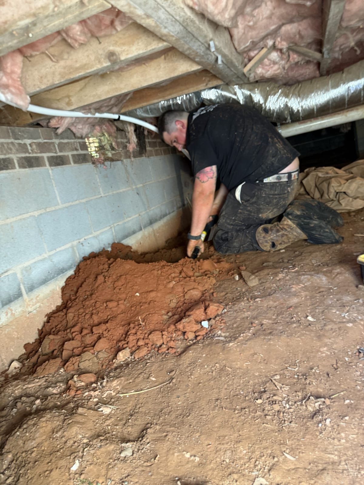 Technician excavating in a crawl space to reach underground plumbing
