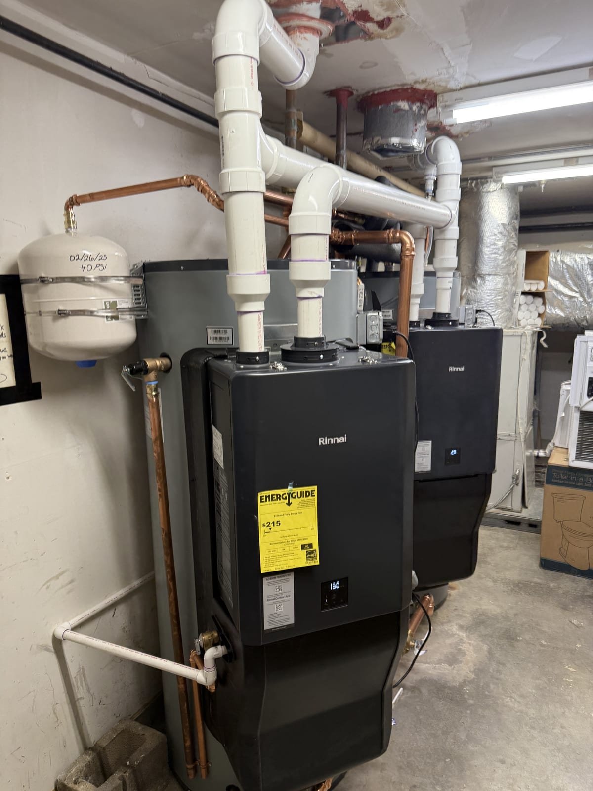 Two commercial Rinnai Demand Duo water heaters installed in a mechanical room