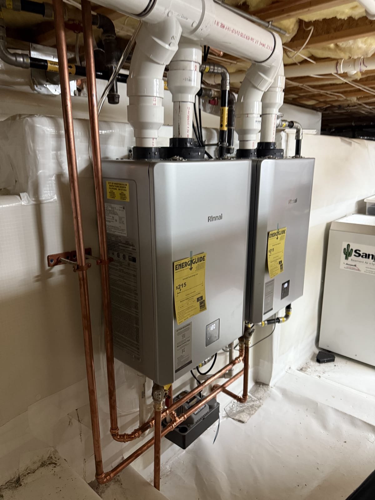 Two tankless water heaters installed side by side and manifolded together