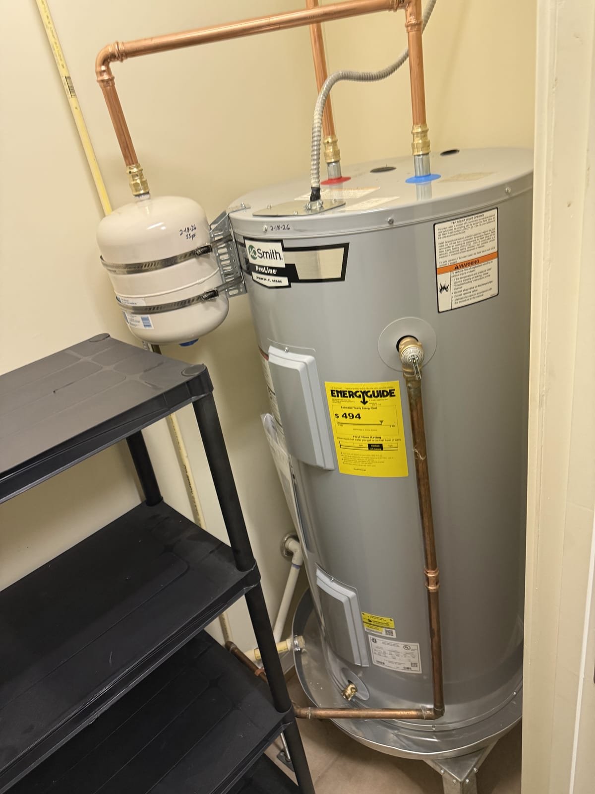 Electric water heater installed in a utility closet with shutoff valve above