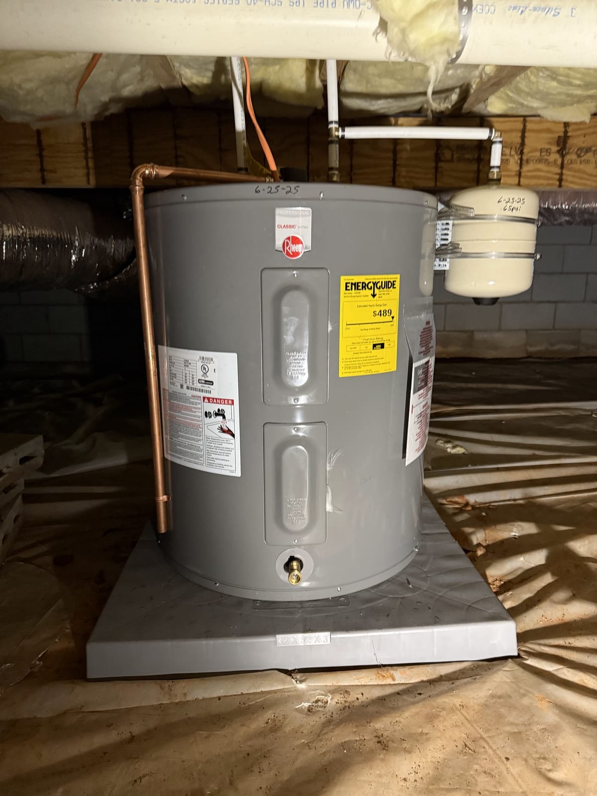 Electric water heater installed in a crawl space on a raised platform