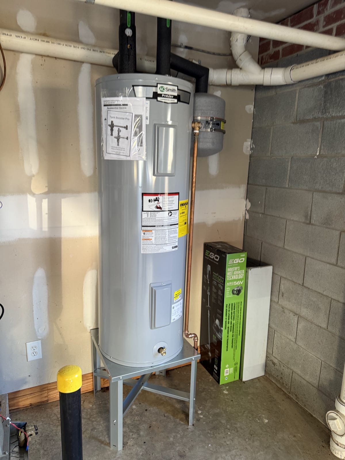 Electric storage tank water heater installed against a finished wall
