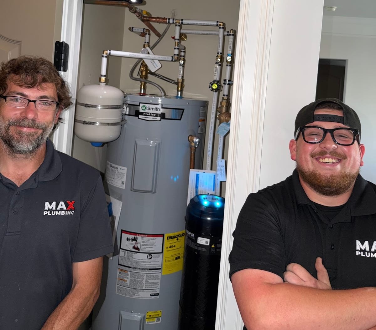 Two MAX Plumbing technicians standing beside a completed water heater installation