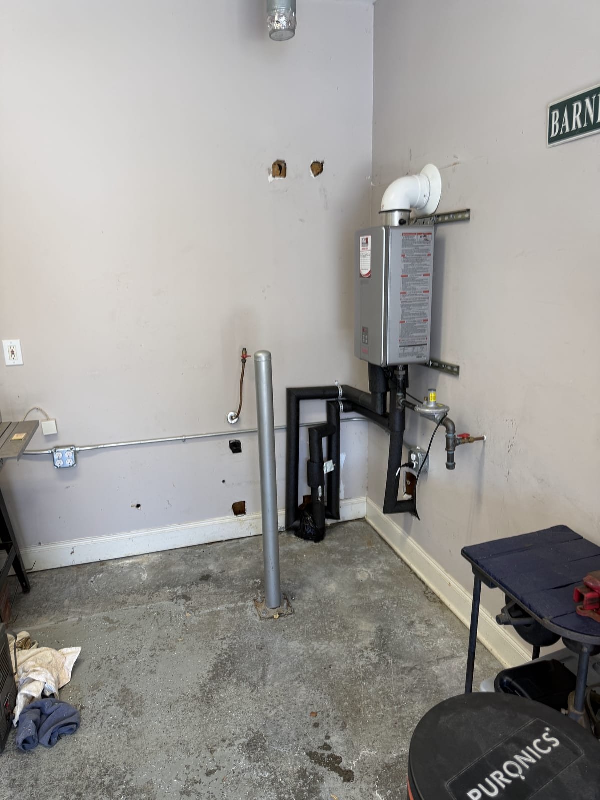 Tankless water heater mounted on an interior wall with venting run overhead