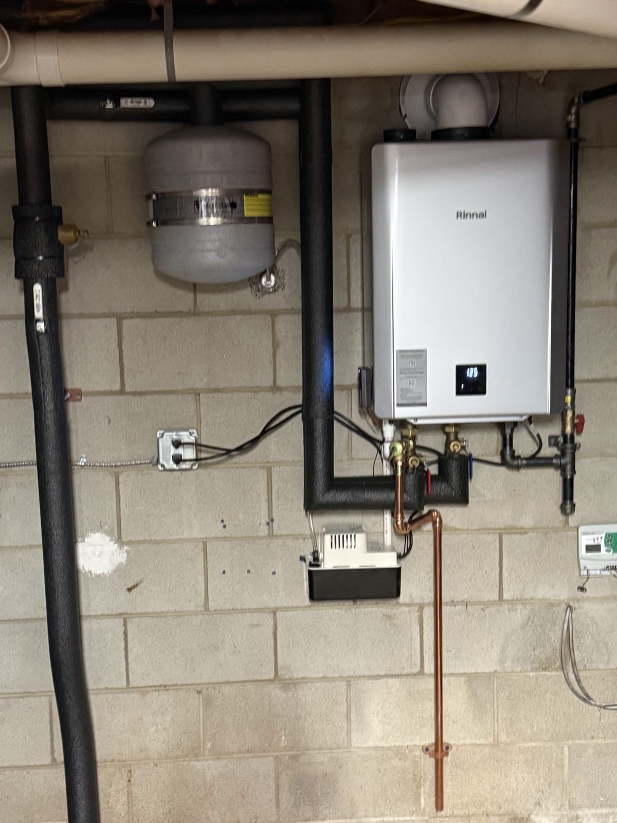 Wall-mounted tankless water heater installed with copper supply lines and isolation valves
