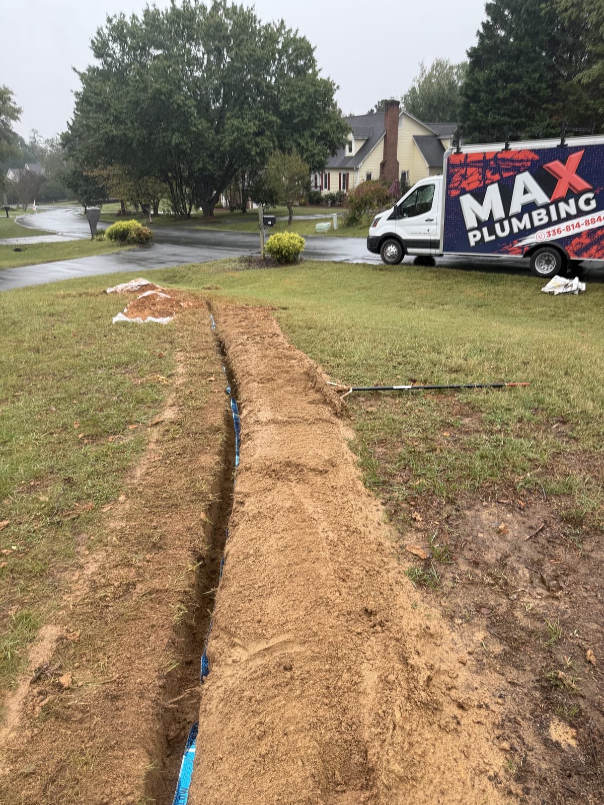 Open trench across a yard prepared for a main water line replacement